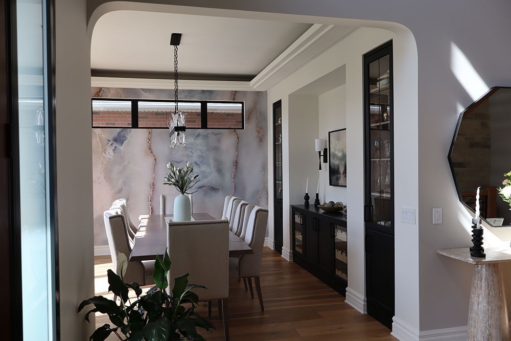 A dining room with a long table and chairs and a mirror.