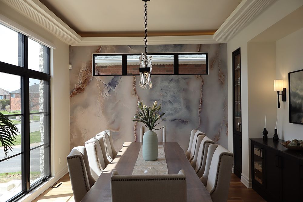 A dining room with a long table and chairs and a vase of flowers on it.