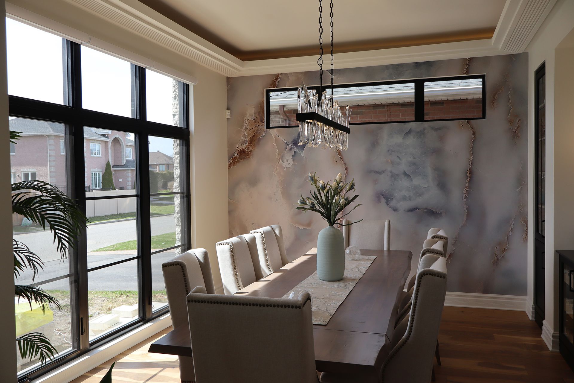 A dining room with a long table and chairs and a large window.