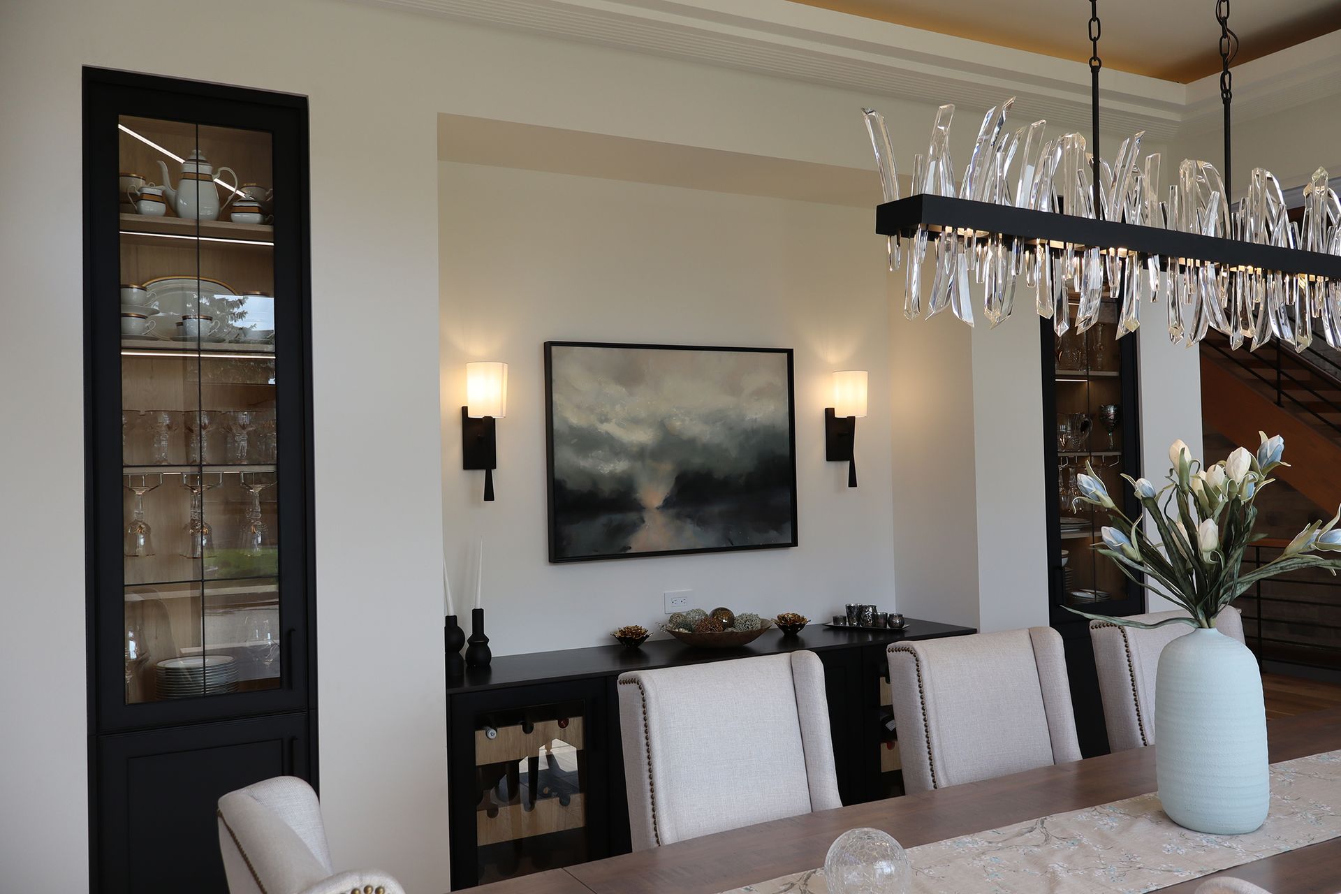A dining room with a painting on the wall above the table