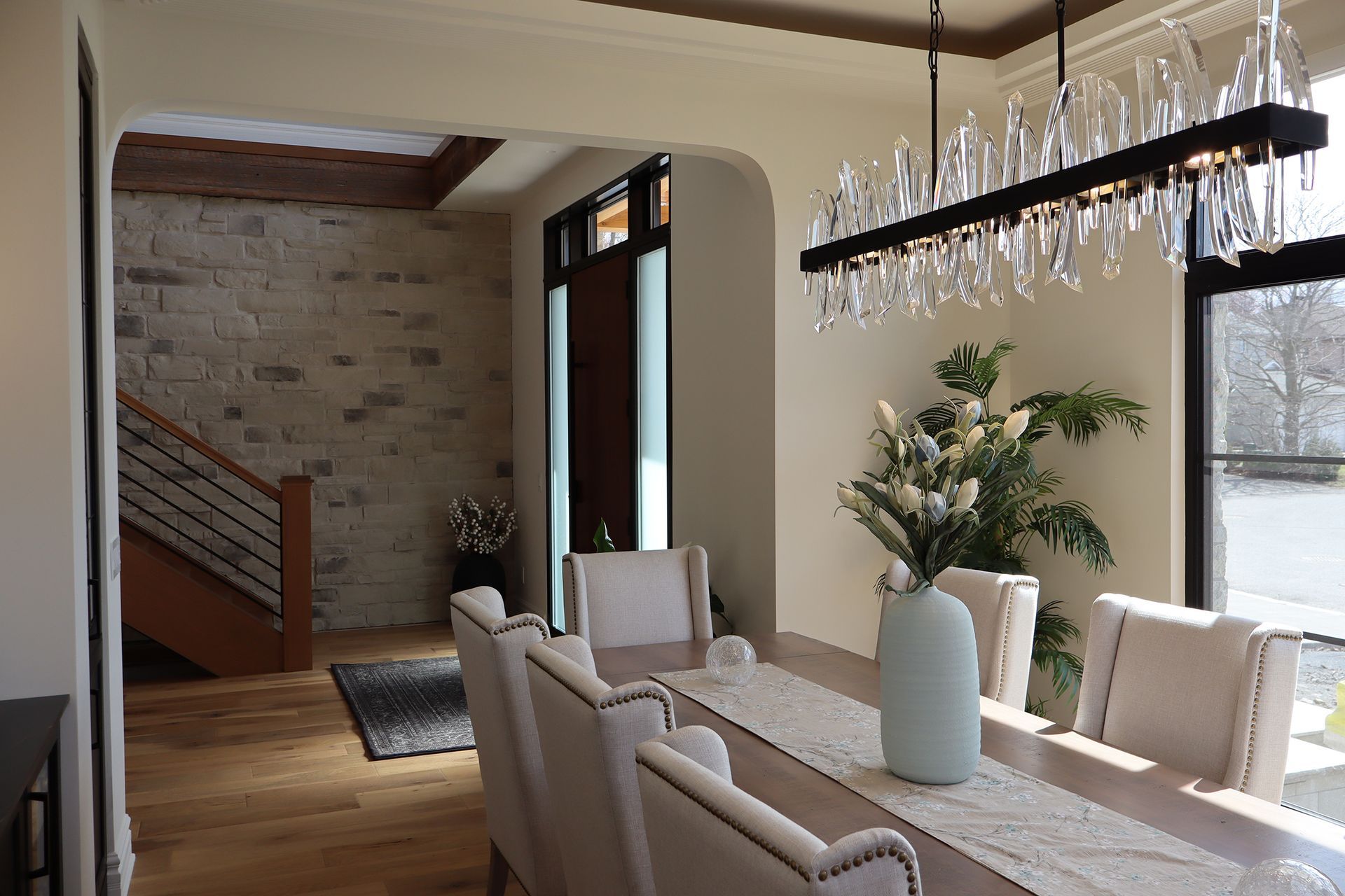 A dining room with a long table and chairs and a chandelier hanging from the ceiling.