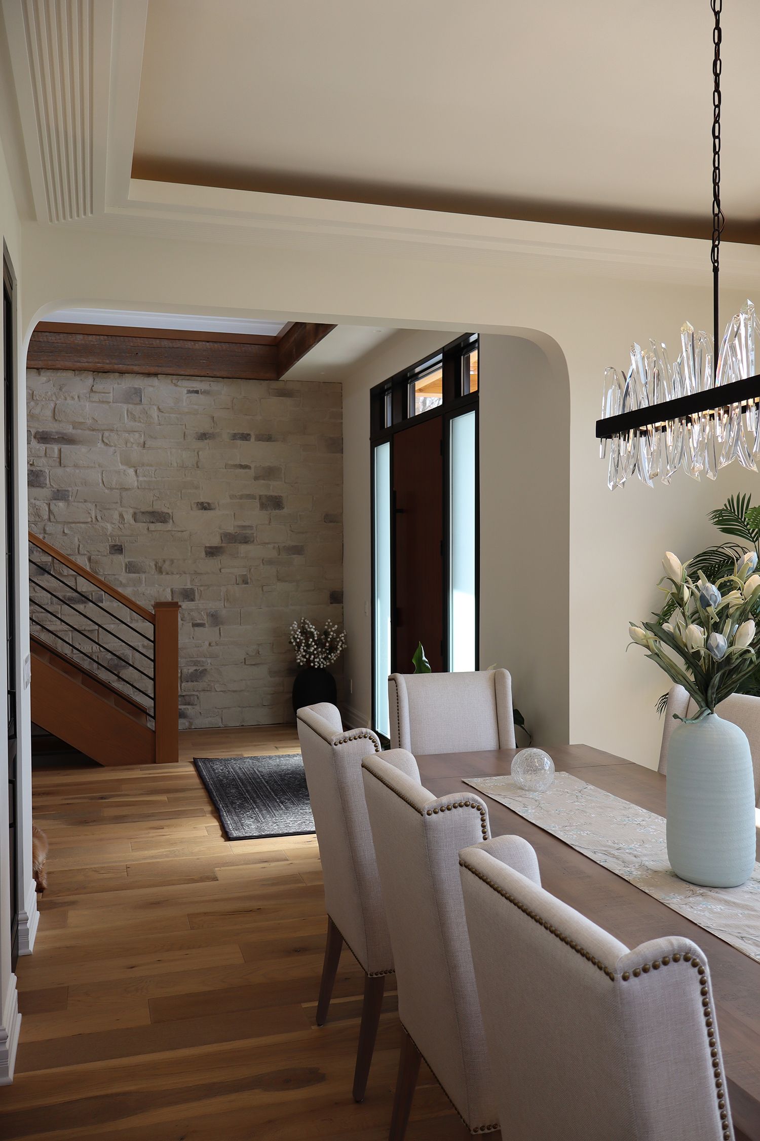 A dining room with a long table and chairs and a chandelier hanging from the ceiling.