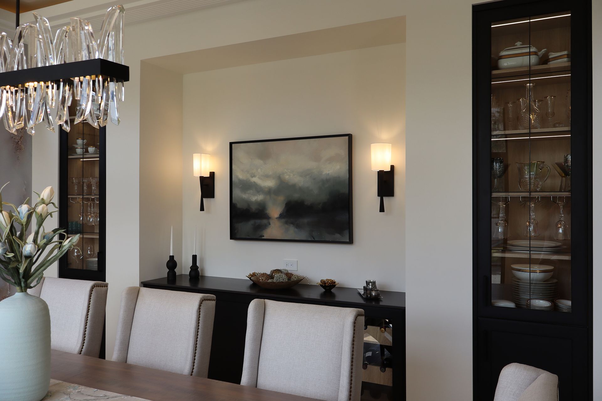 A dining room with a table and chairs and a painting on the wall