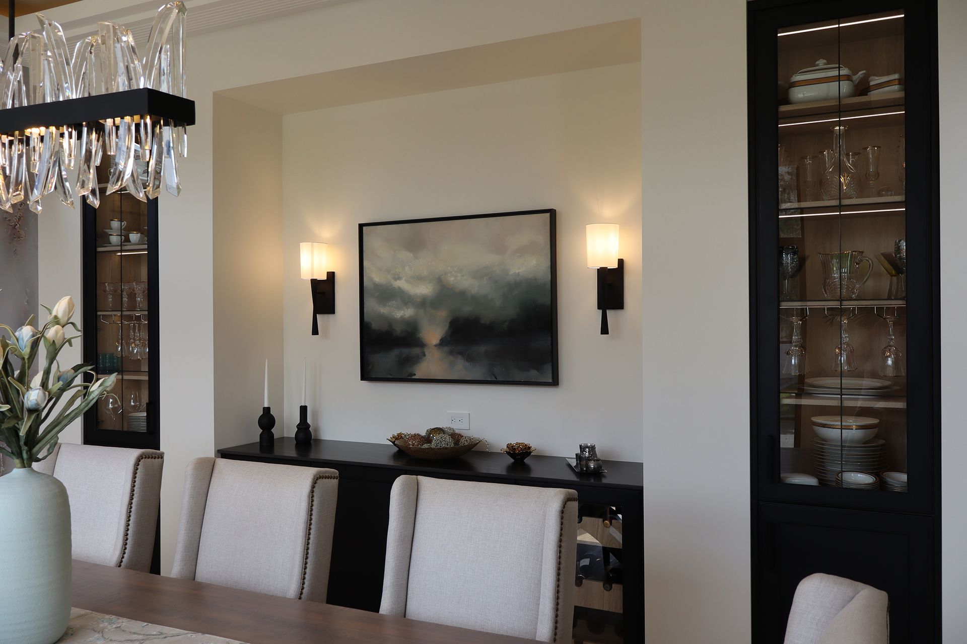 A dining room with a painting on the wall above the table