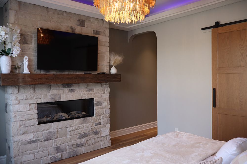 A bedroom with a fireplace , television and sliding barn door.