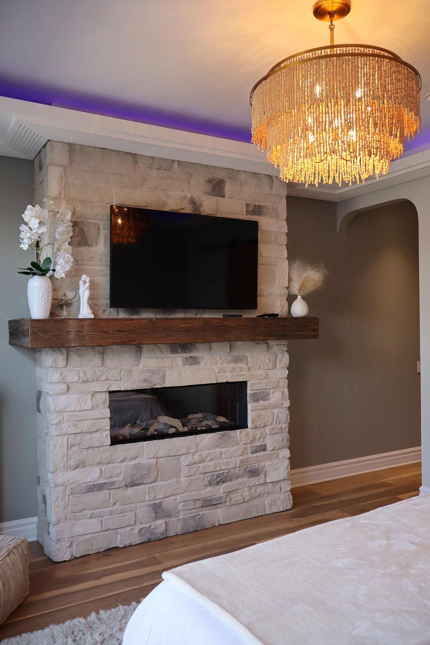 A living room with a fireplace , television and chandelier.