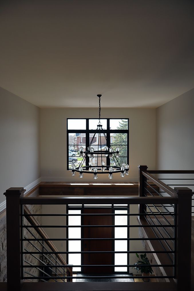 A staircase with a chandelier hanging from the ceiling and a window.