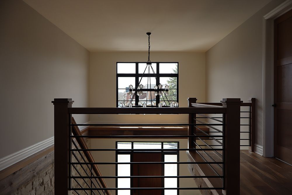 A staircase in a house with a chandelier hanging from the ceiling.