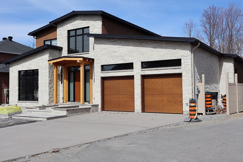 A large house with two garage doors is under construction.