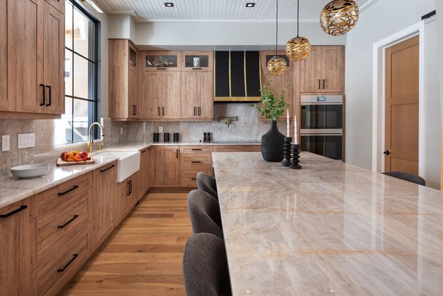 A kitchen with wooden cabinets , granite counter tops , and a large island.