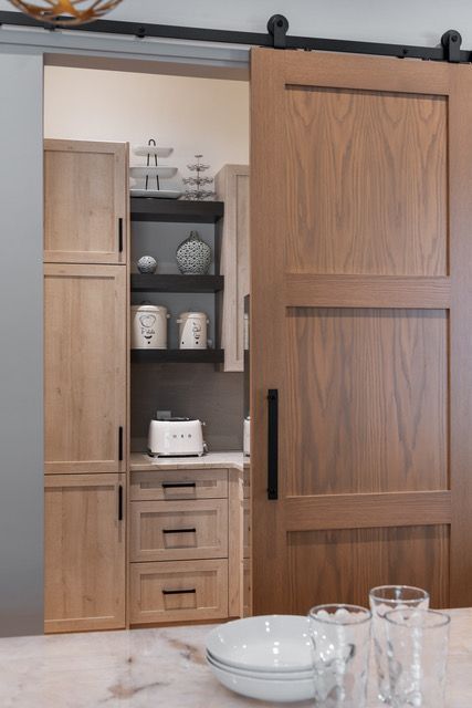 A kitchen with a sliding barn door and plates and glasses on the table