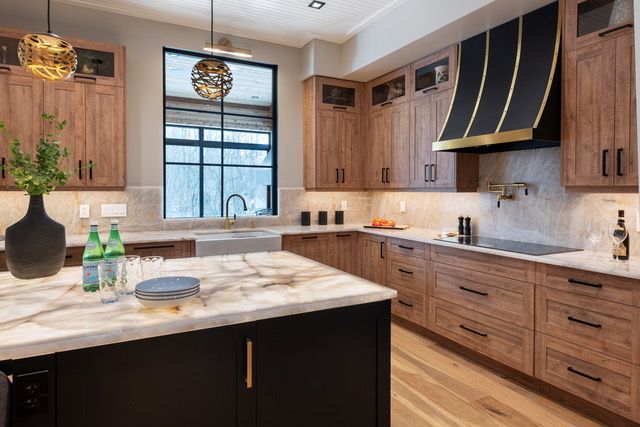 A kitchen with wooden cabinets , granite counter tops , and a large island.
