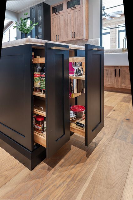 A kitchen with black cabinets and wooden floors