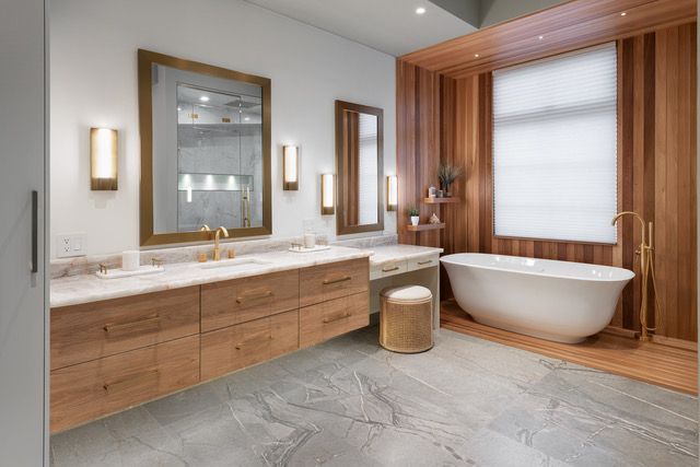 A bathroom with a tub , sinks , mirrors and wooden cabinets.