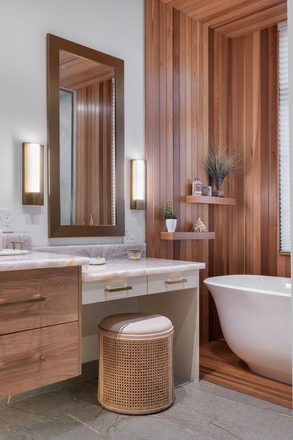 A bathroom with a tub , sink , mirror and stool
