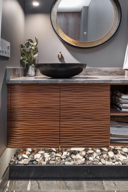 A bathroom with a sink , mirror , and wooden cabinets.