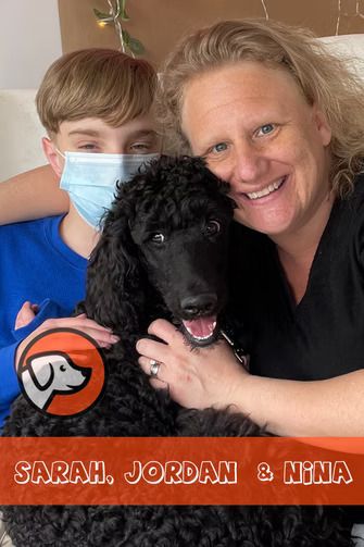 A smiling woman and a person in a blue shirt and face mask pose with a black poodle, text reads 