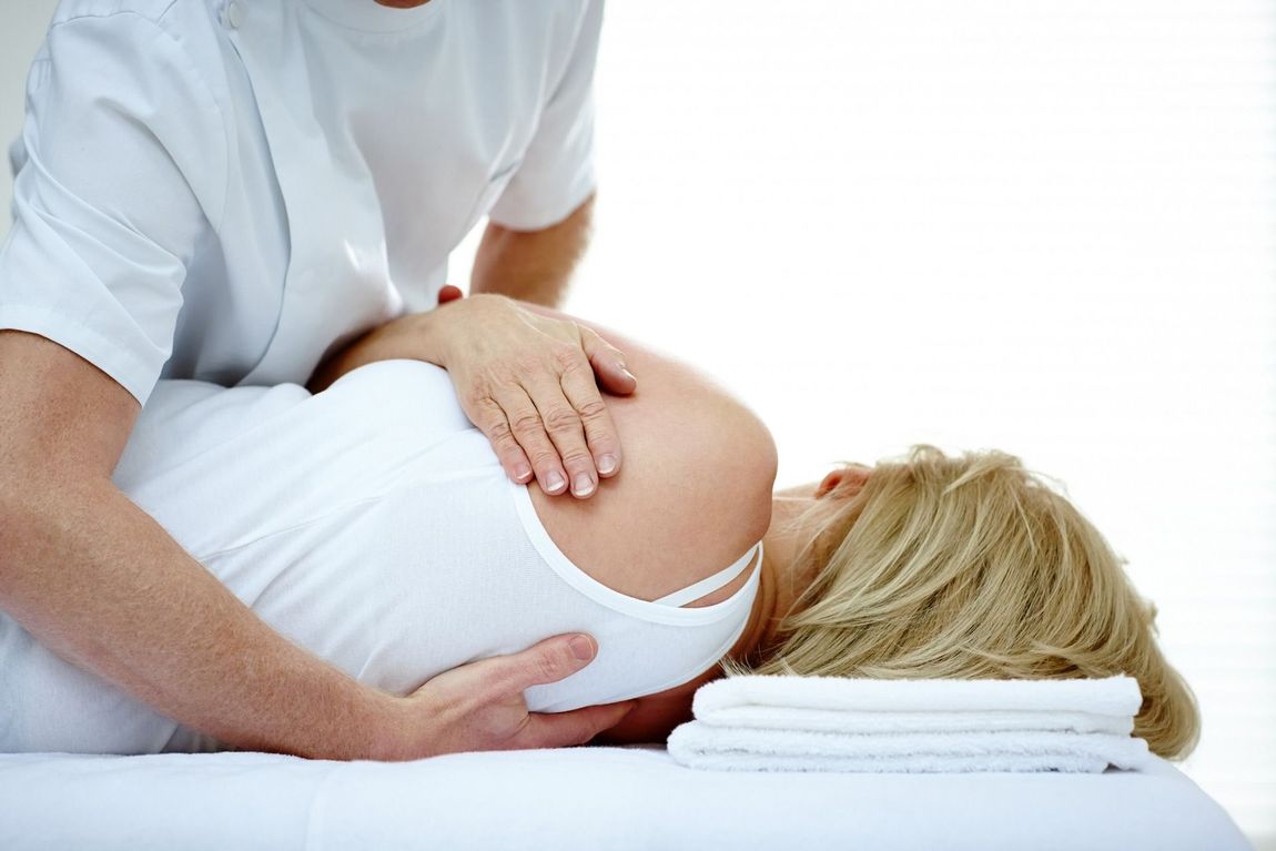 A woman is laying on a table getting a massage from a man