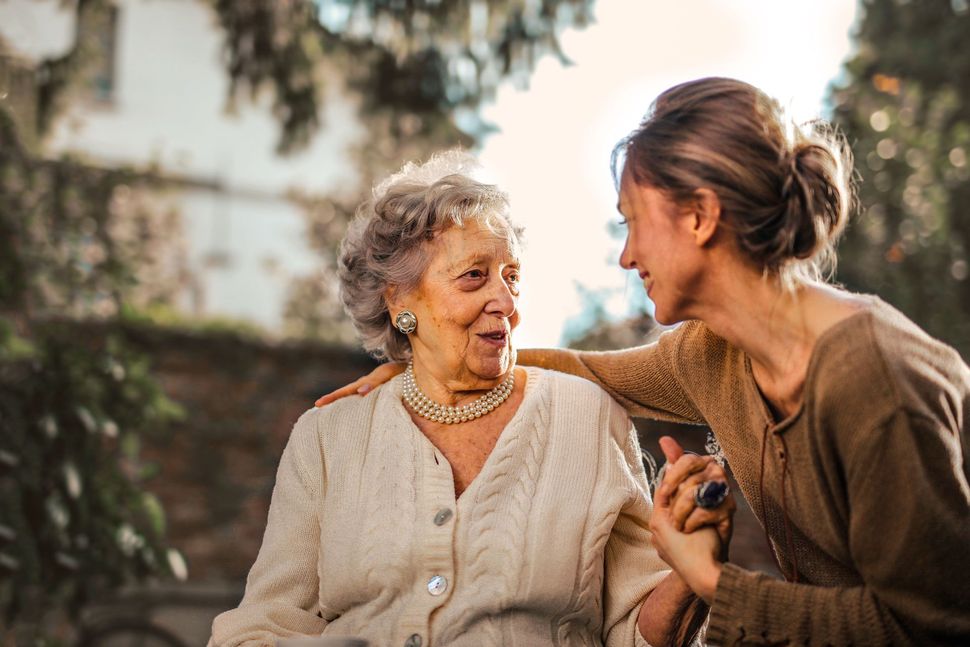 Two women sitting outdoors, smiling and talking in a garden at sunset