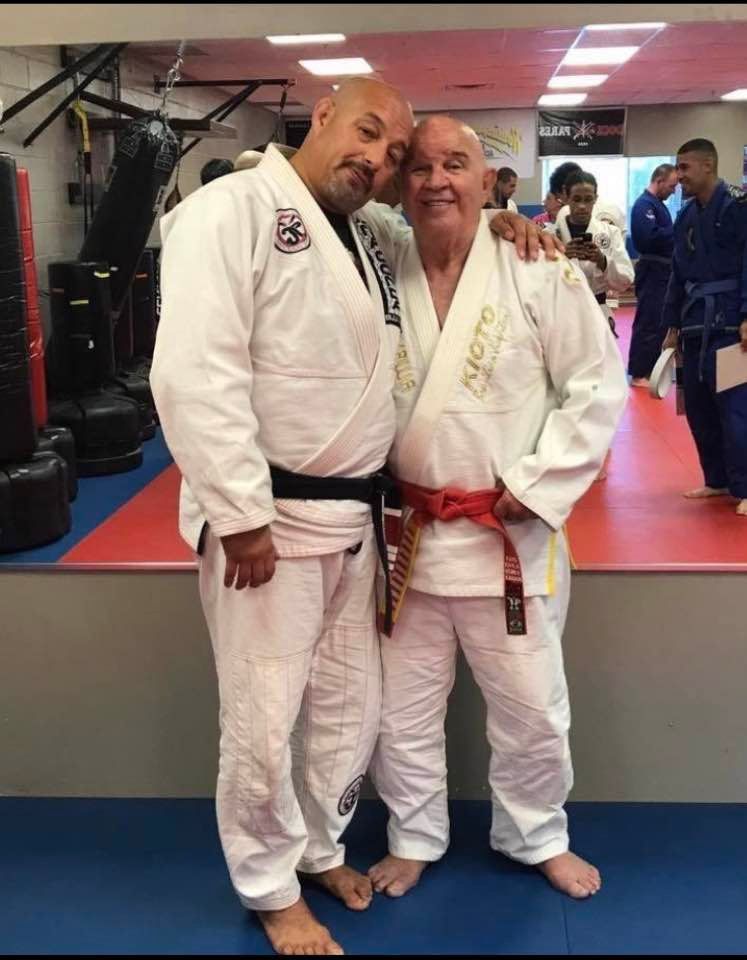Two men in karate uniforms are posing for a picture in a gym.