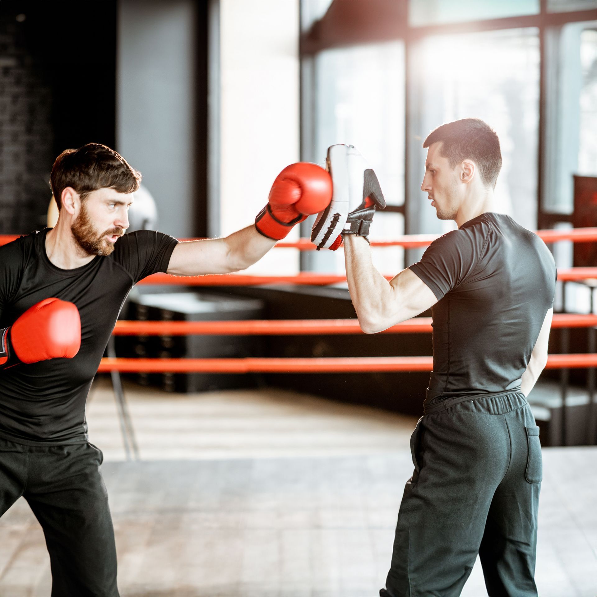 two men wearing red boxing gloves are sparring in a gym