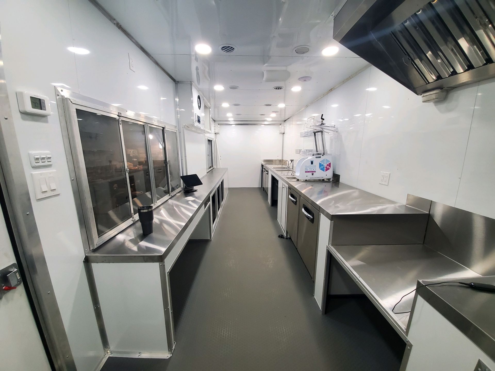 Interior of a modern kitchen trailer featuring stainless steel appliances, countertops, and bright lighting