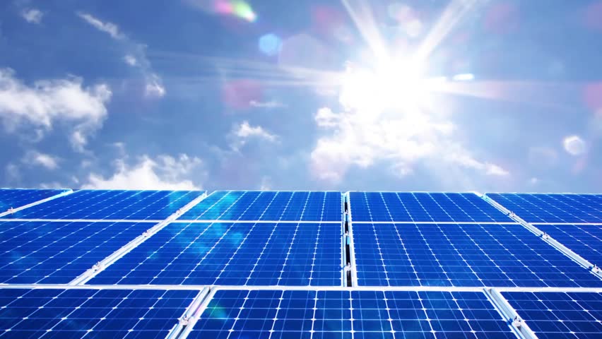 Solar panels under a bright blue sky with the sun shining overhead