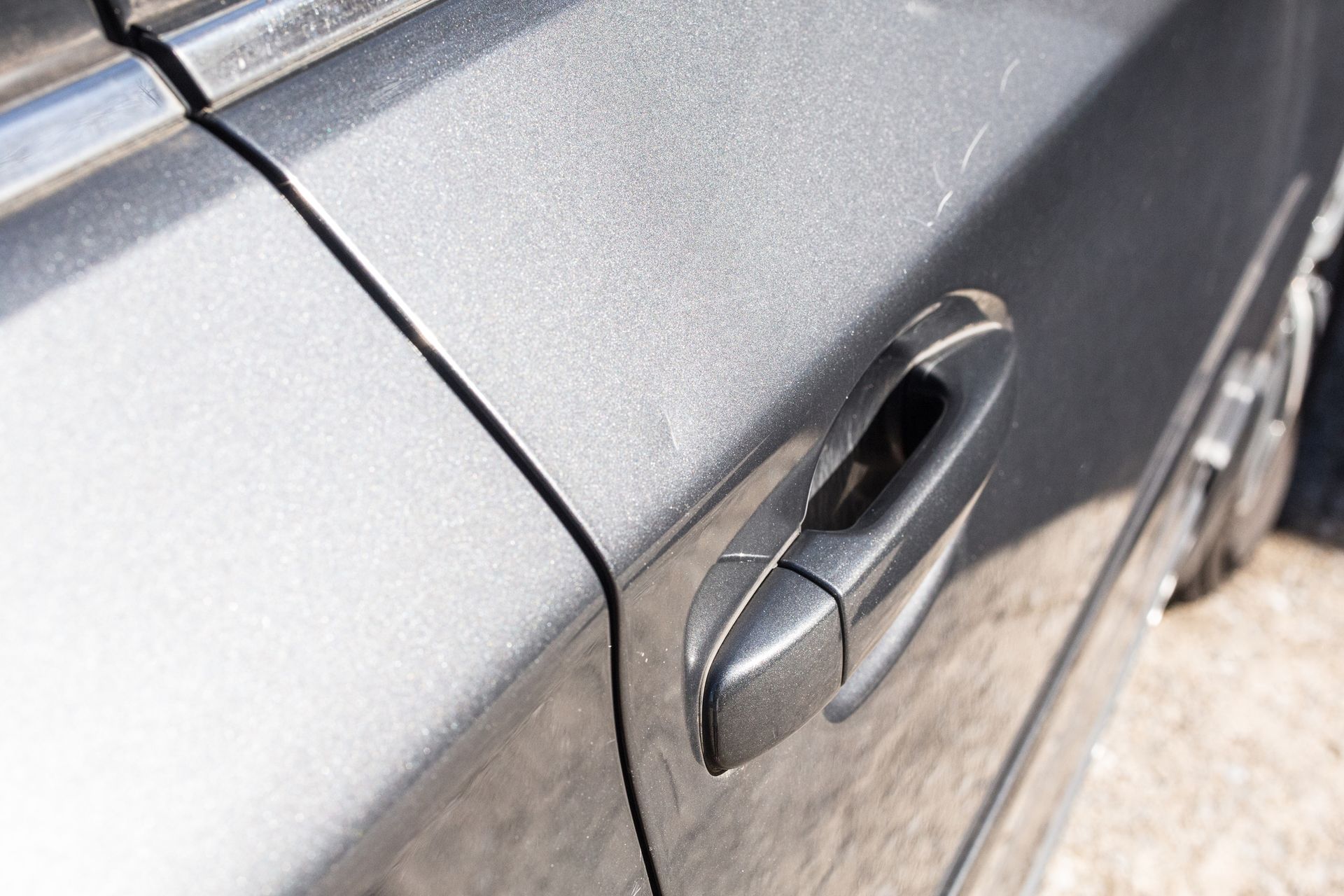 Gray car door with a black handle; close-up.