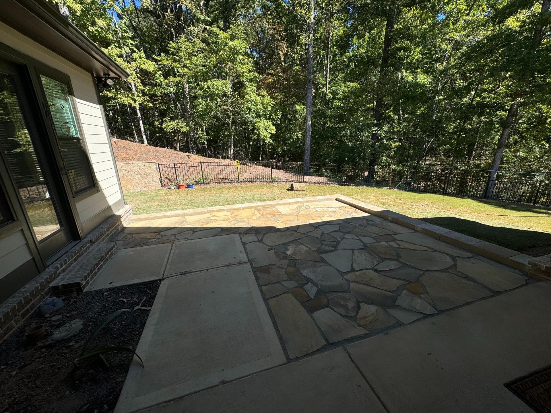 A stone patio in front of a house with trees in the background.