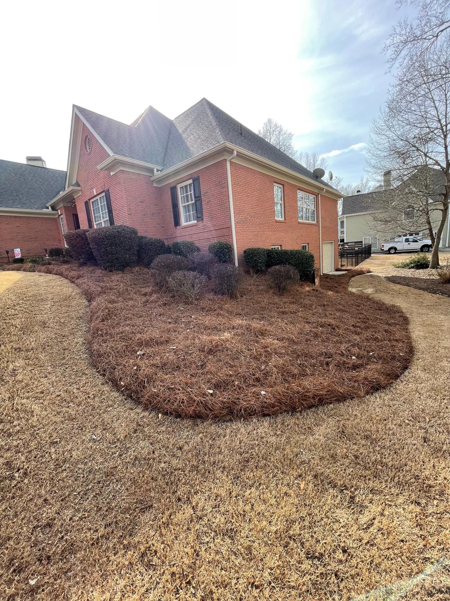 A large brick house with a lot of mulch in front of it.