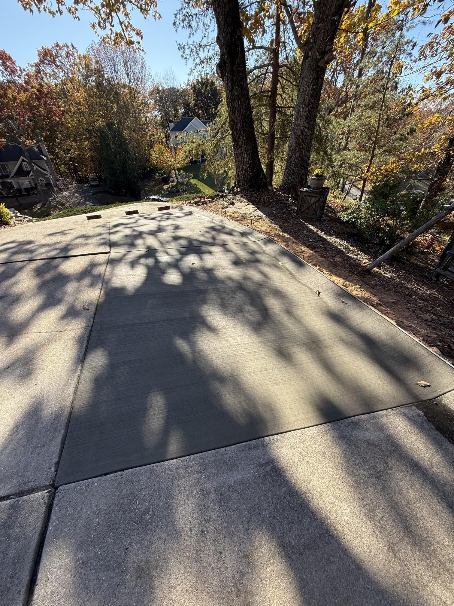 A concrete driveway with trees casting shadows on it.