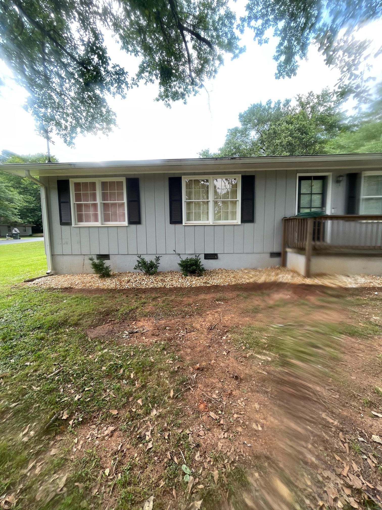 A gray house with black shutters and a porch