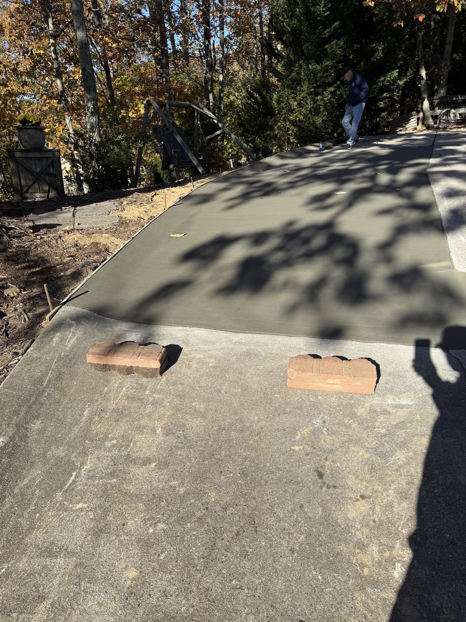 A concrete driveway with bricks on the side of it.