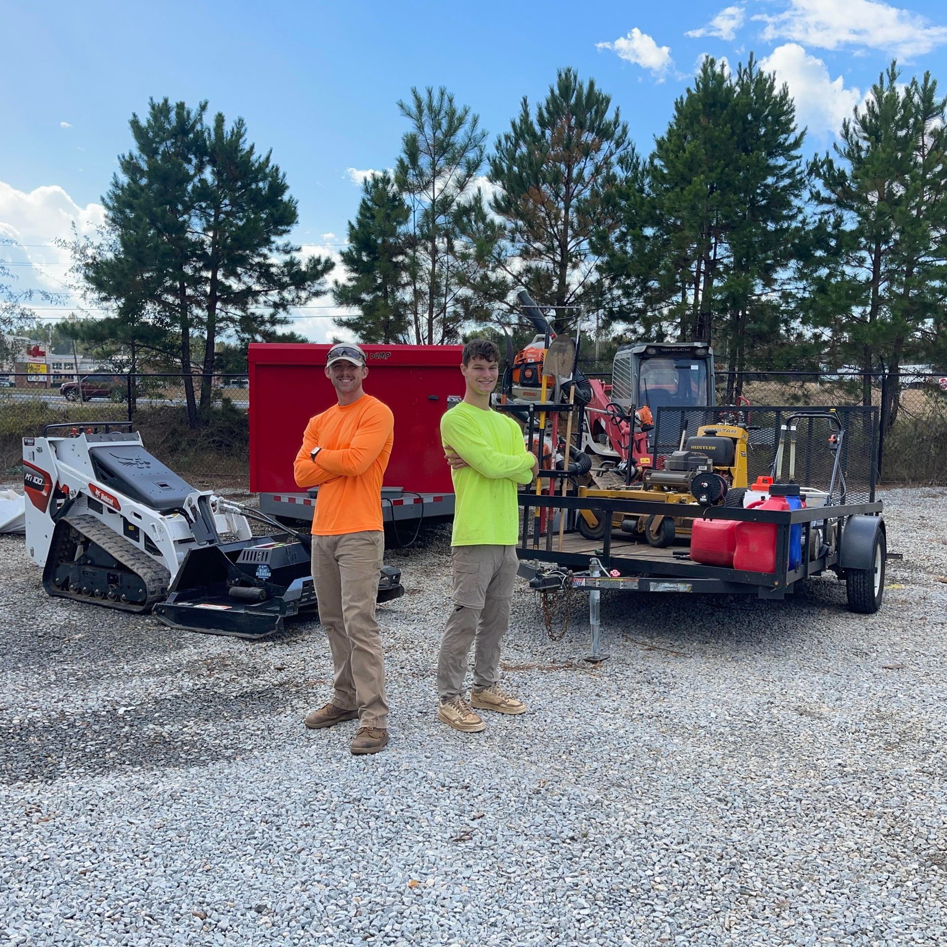 Two men are standing in front of a trailer with a bulldozer on it.