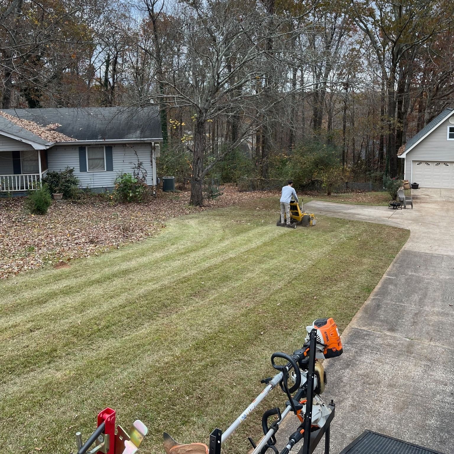 A man is mowing a lush green lawn in front of a house.