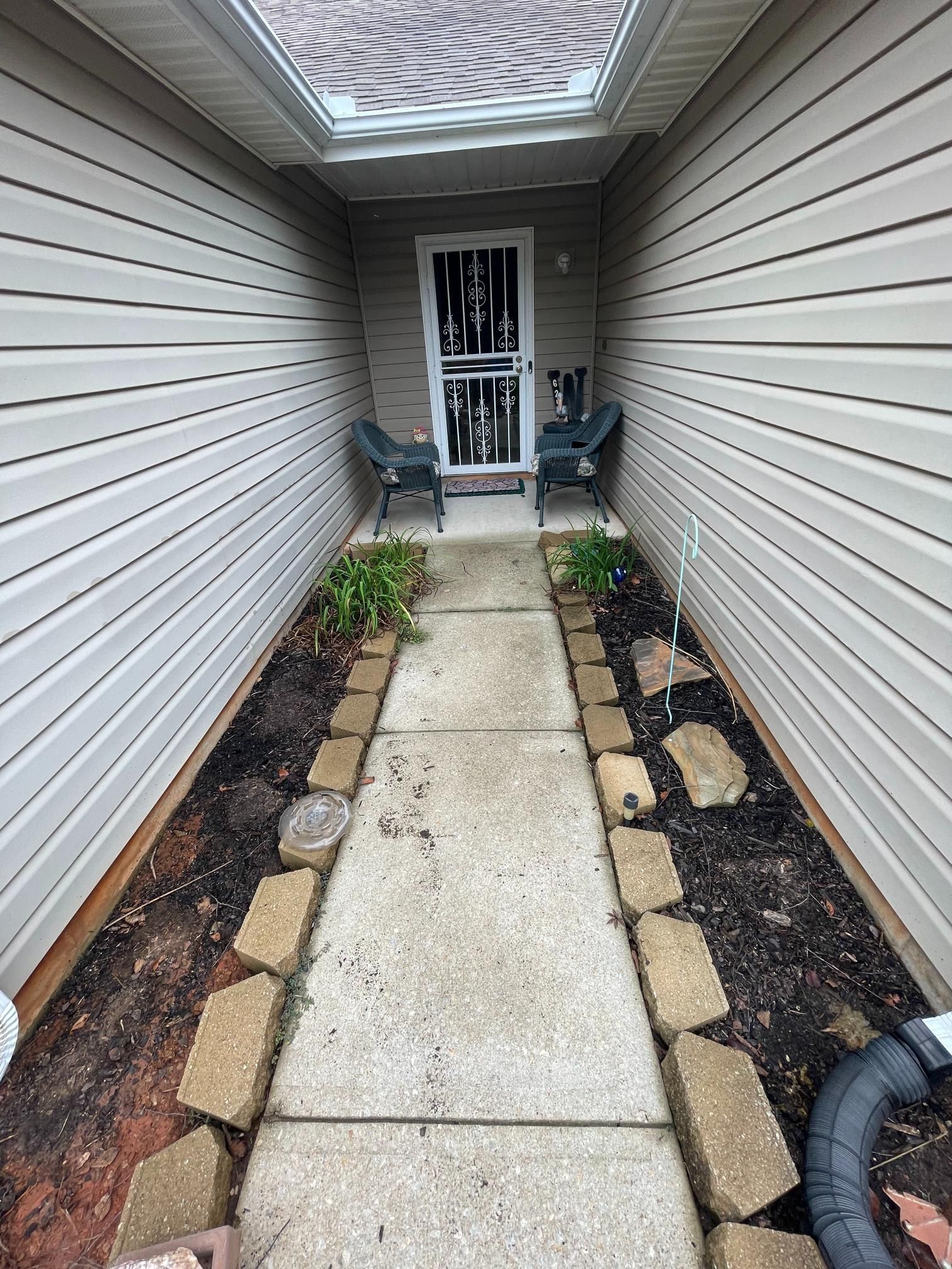 A narrow walkway leading to the front door of a house.