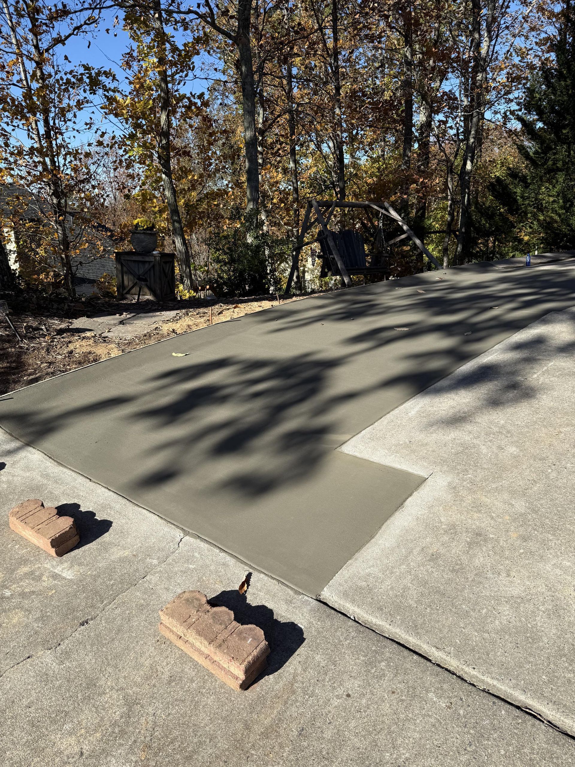 A concrete driveway with bricks on the side of it and trees in the background.