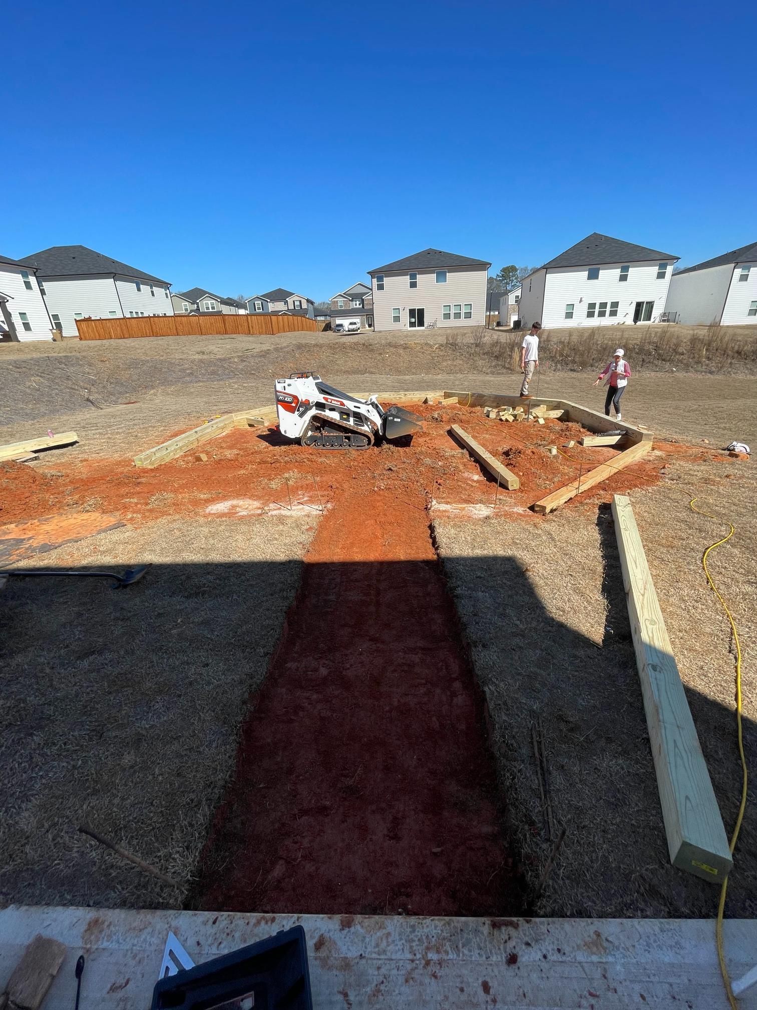 A construction site with a lot of dirt and houses in the background.