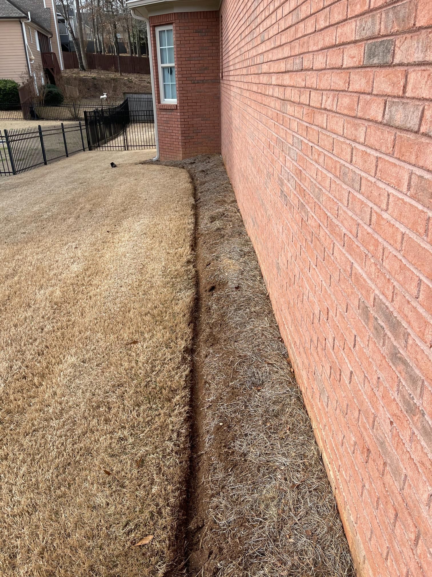 A brick wall with a hole in the ground in front of it.