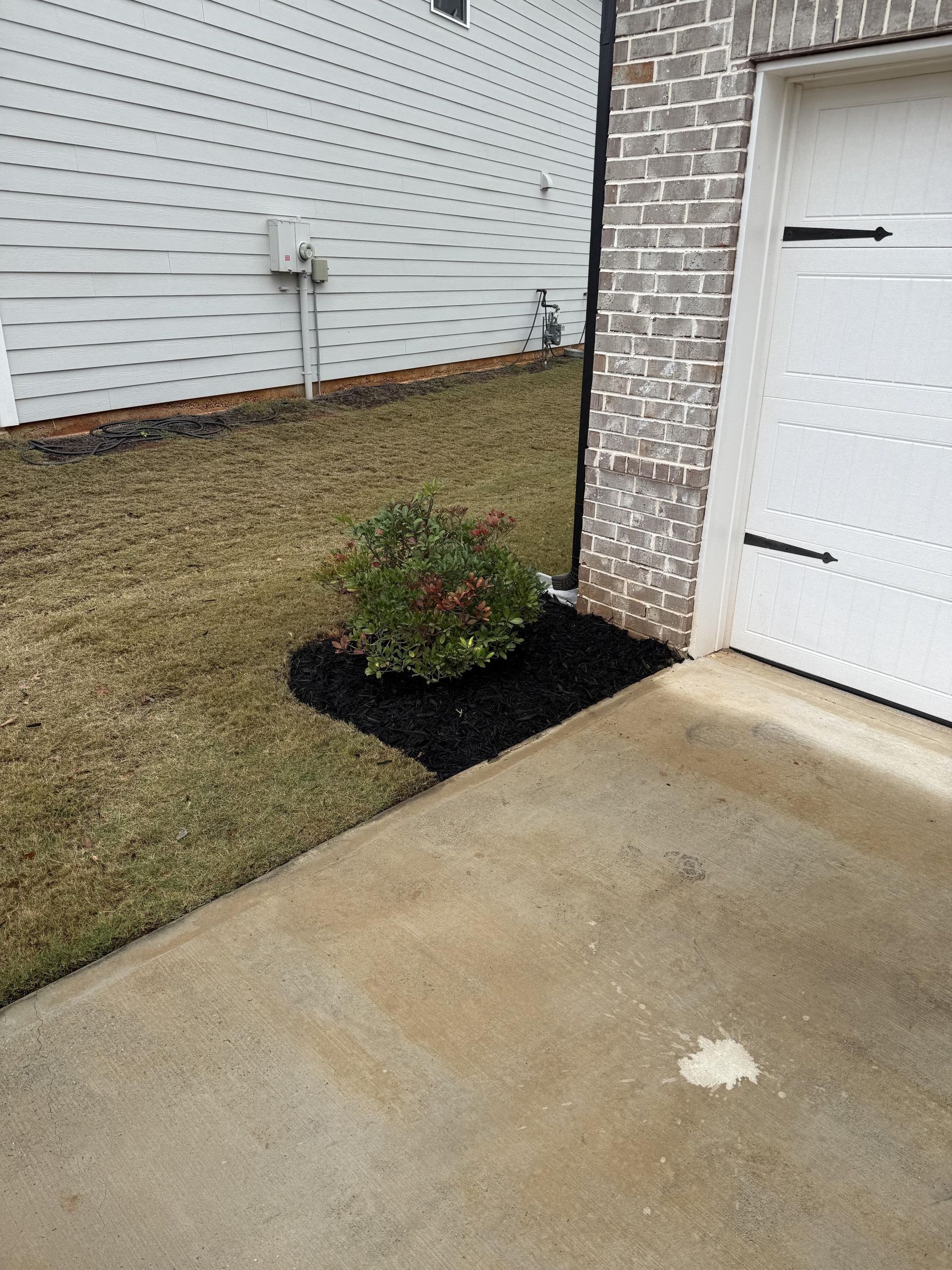 A white garage door is sitting next to a brick building.