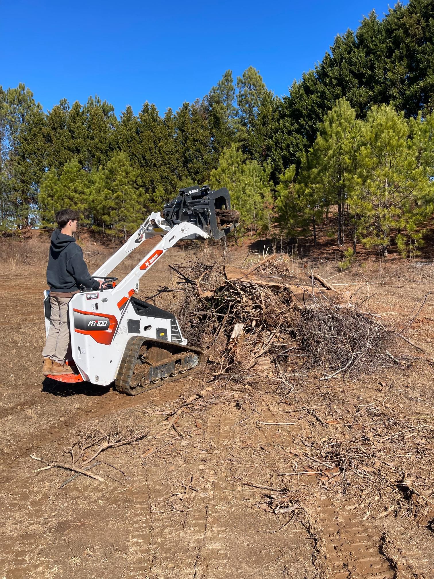 A man is using a stump grinder to remove a tree stump from a field.