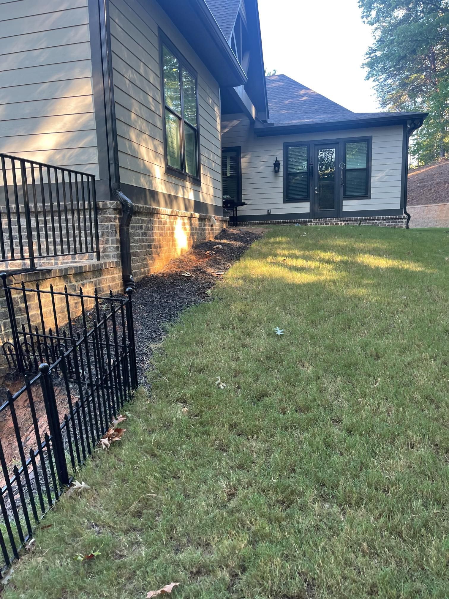A house with a fence around it and a large lawn in front of it.