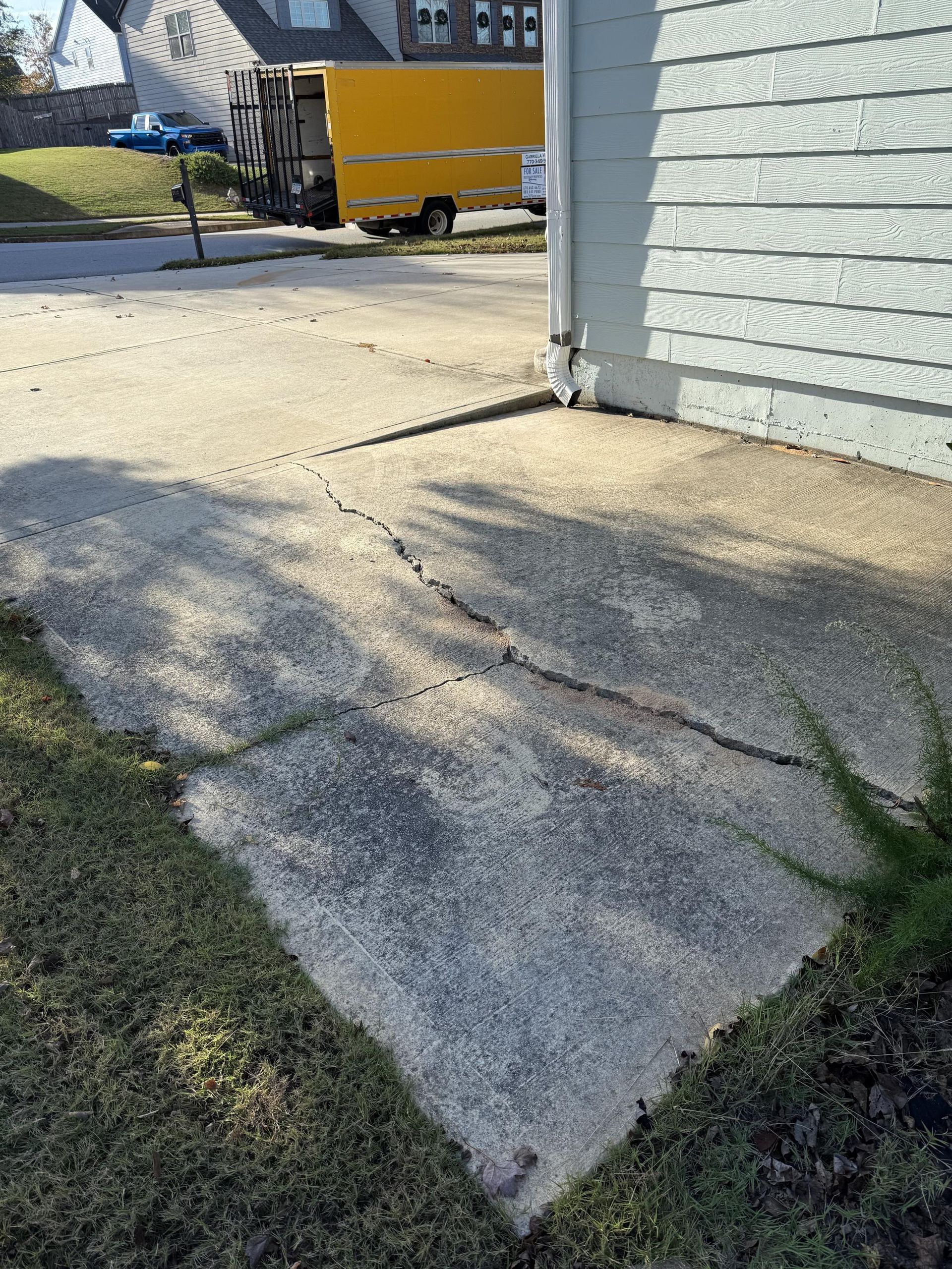 A yellow truck is parked in the driveway of a house.