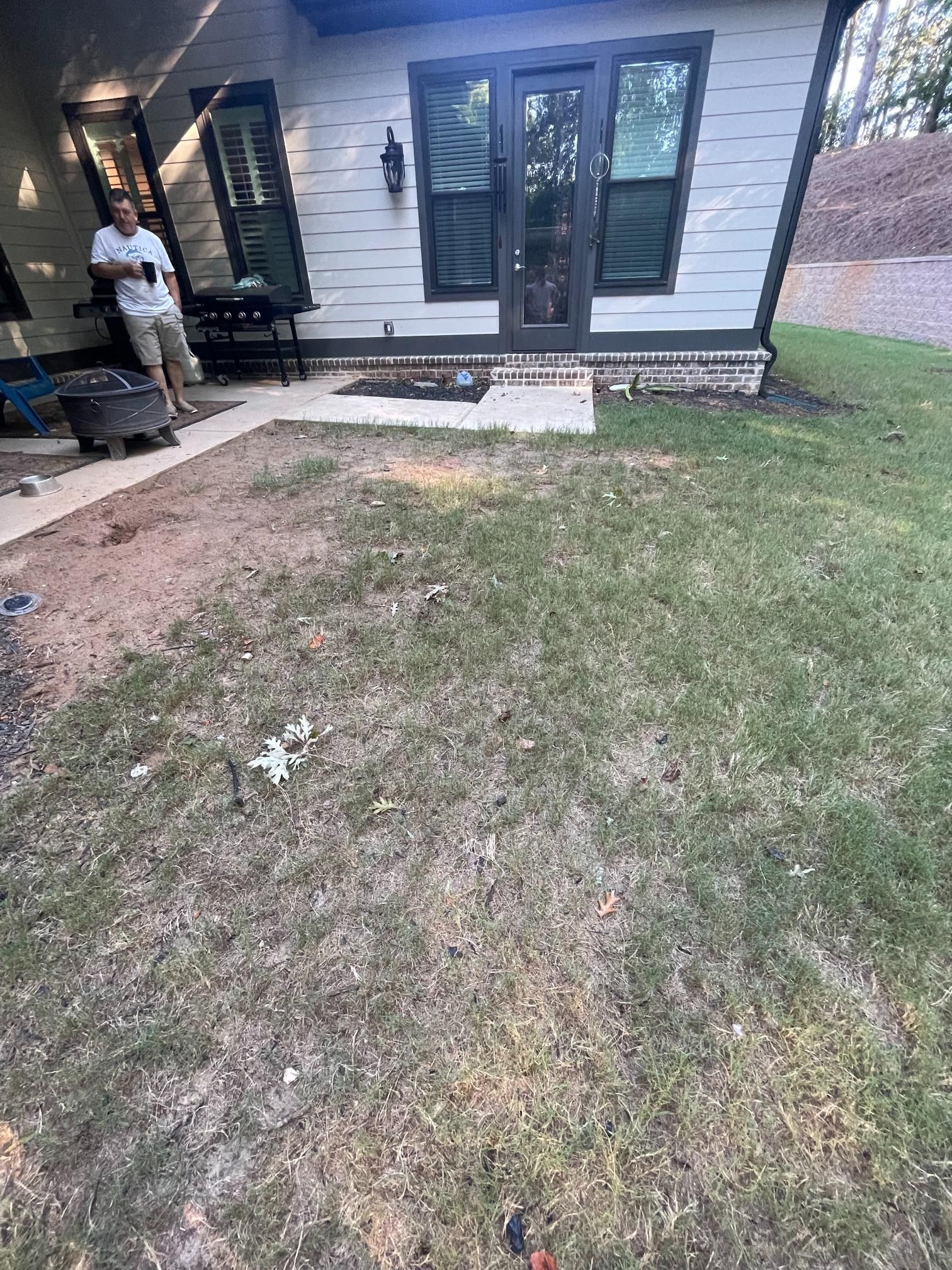 A man is standing in the grass in front of a house.