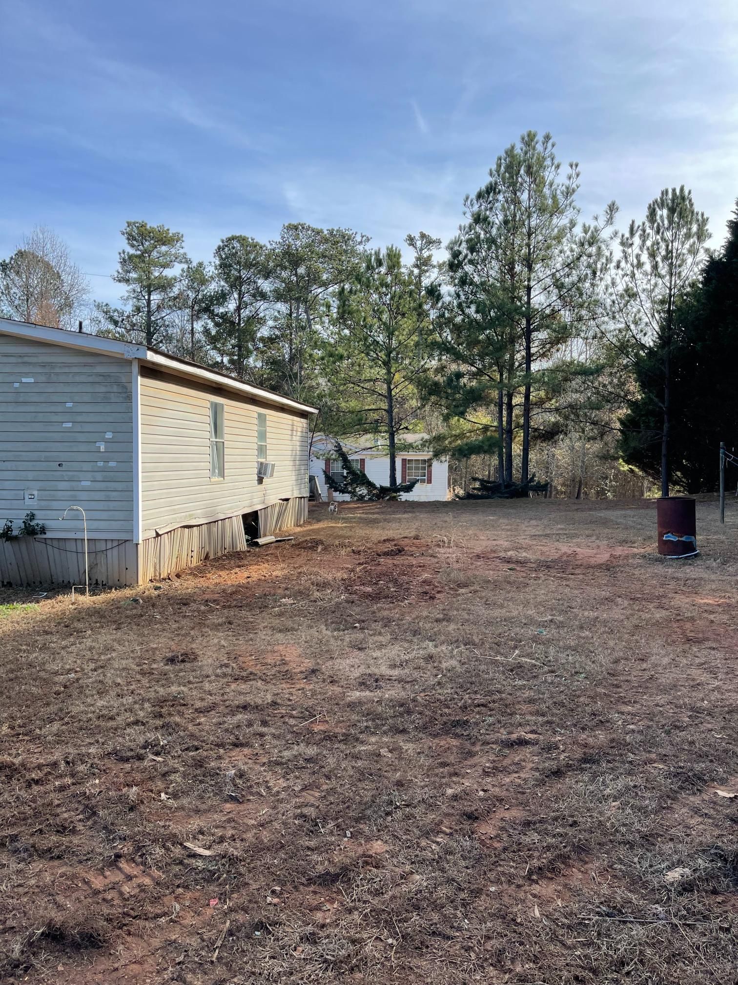 A mobile home is sitting in the middle of a dirt field.