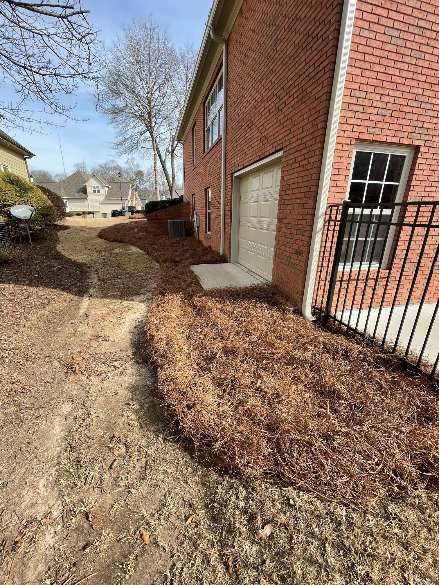 A brick house with a garage and a fence in front of it.