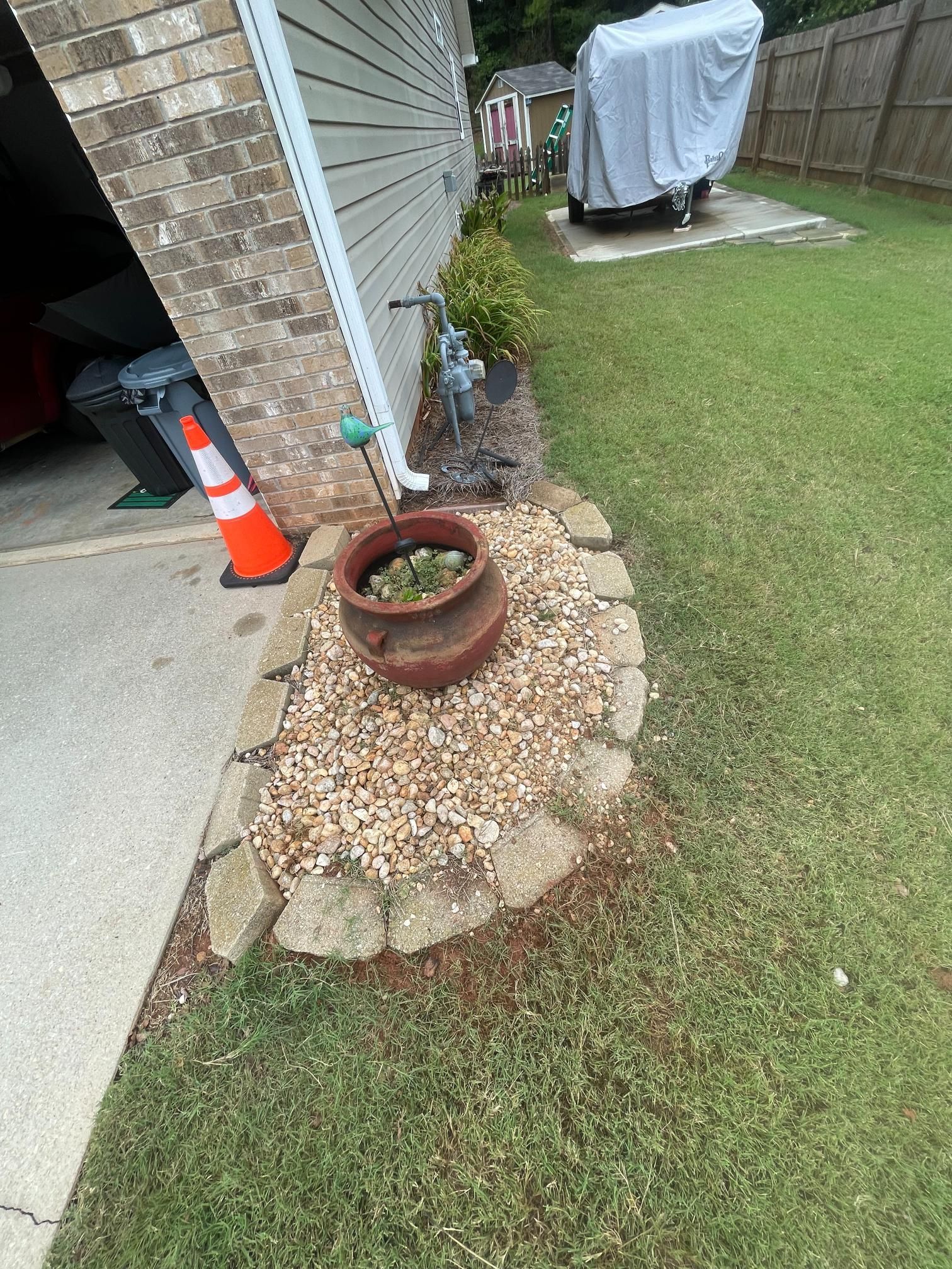 A potted plant is sitting on the side of a house next to a garage.