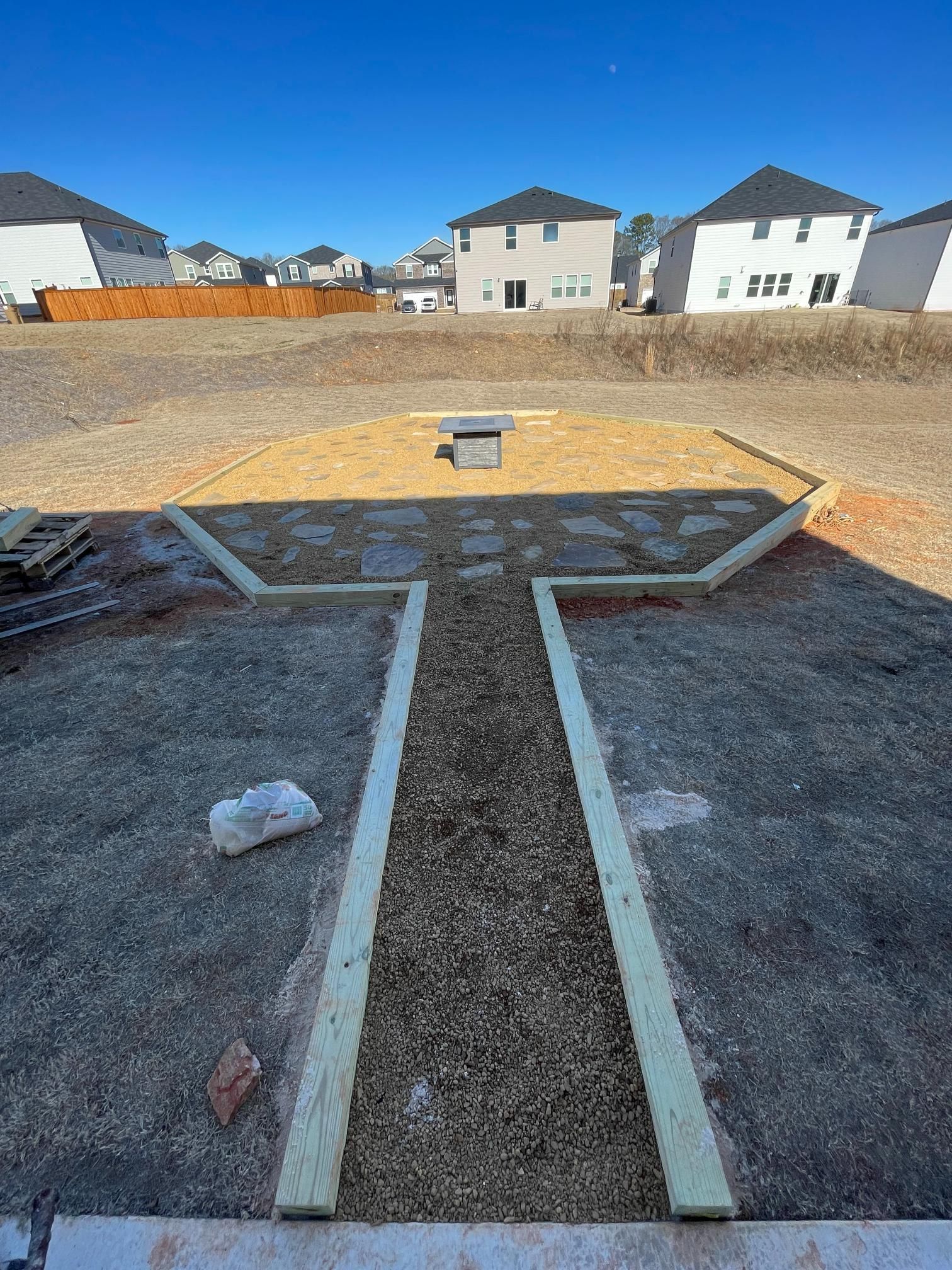 A baseball field under construction with houses in the background.