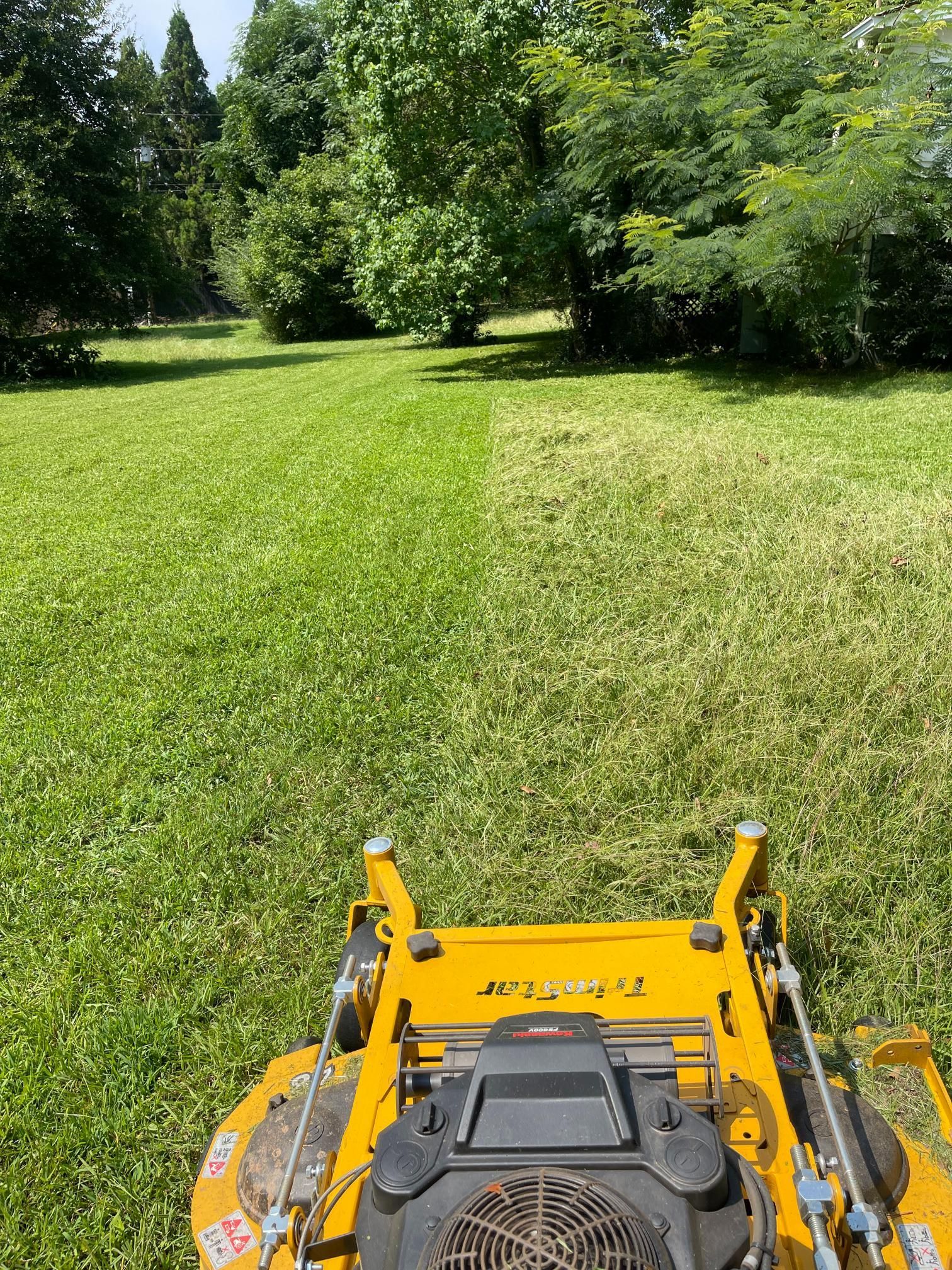 A yellow lawn mower is cutting a lush green lawn.