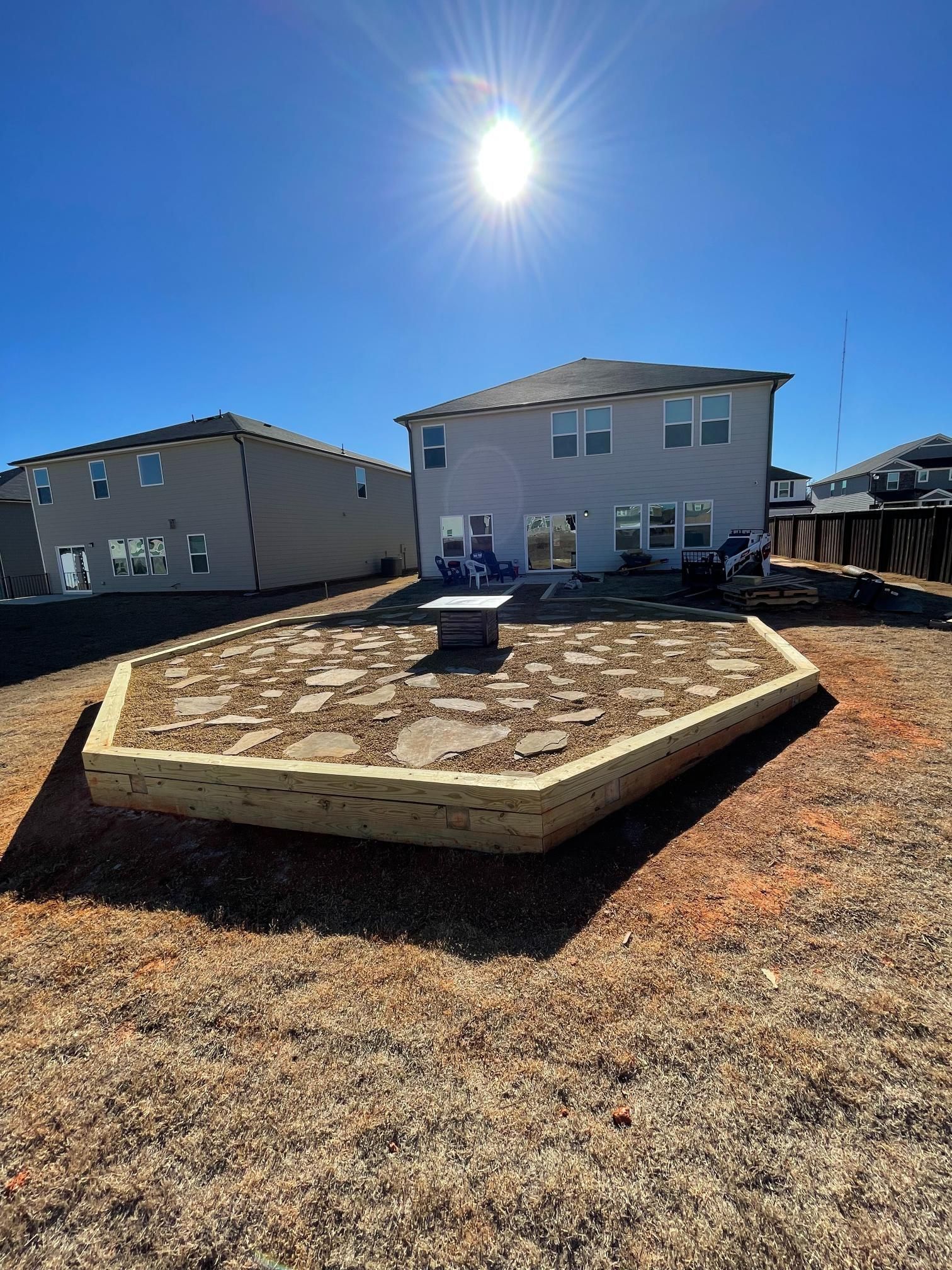 The sun is shining brightly in the backyard of a house.